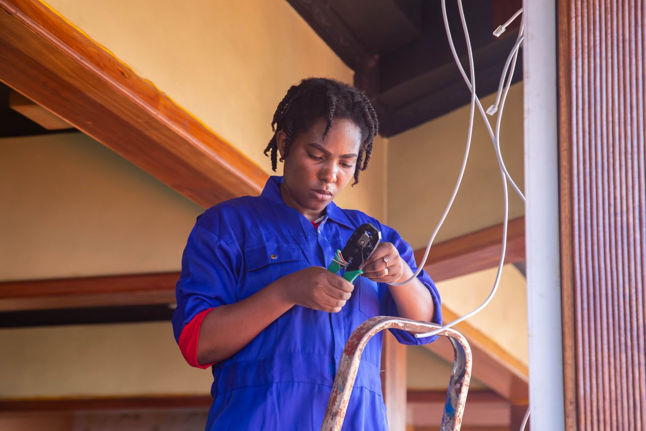 Professional electrician working on wiring in an indoor setting, demonstrating skill and concentration.